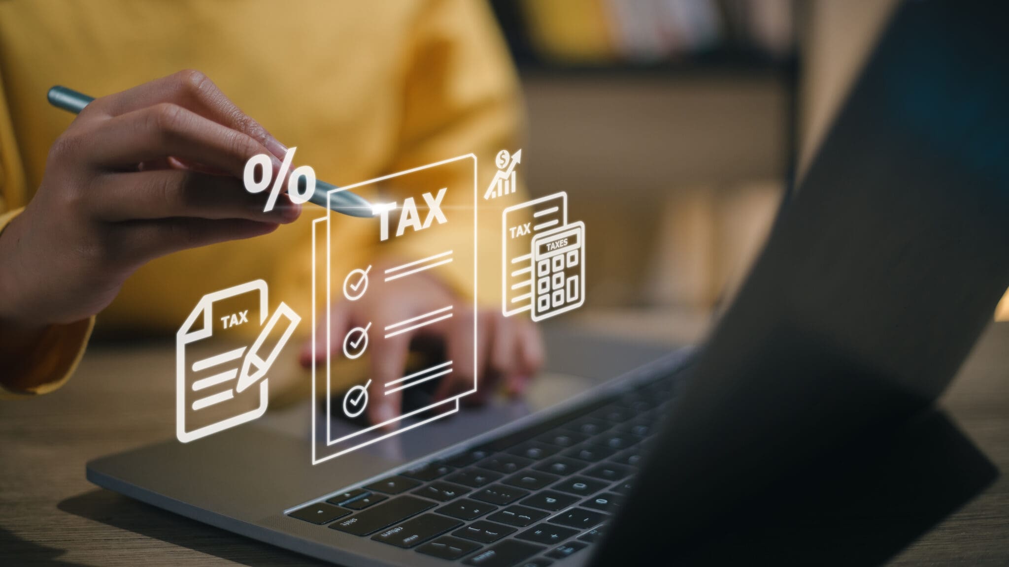 Two people calculating income tax returns in front of a laptop displaying a holographic.