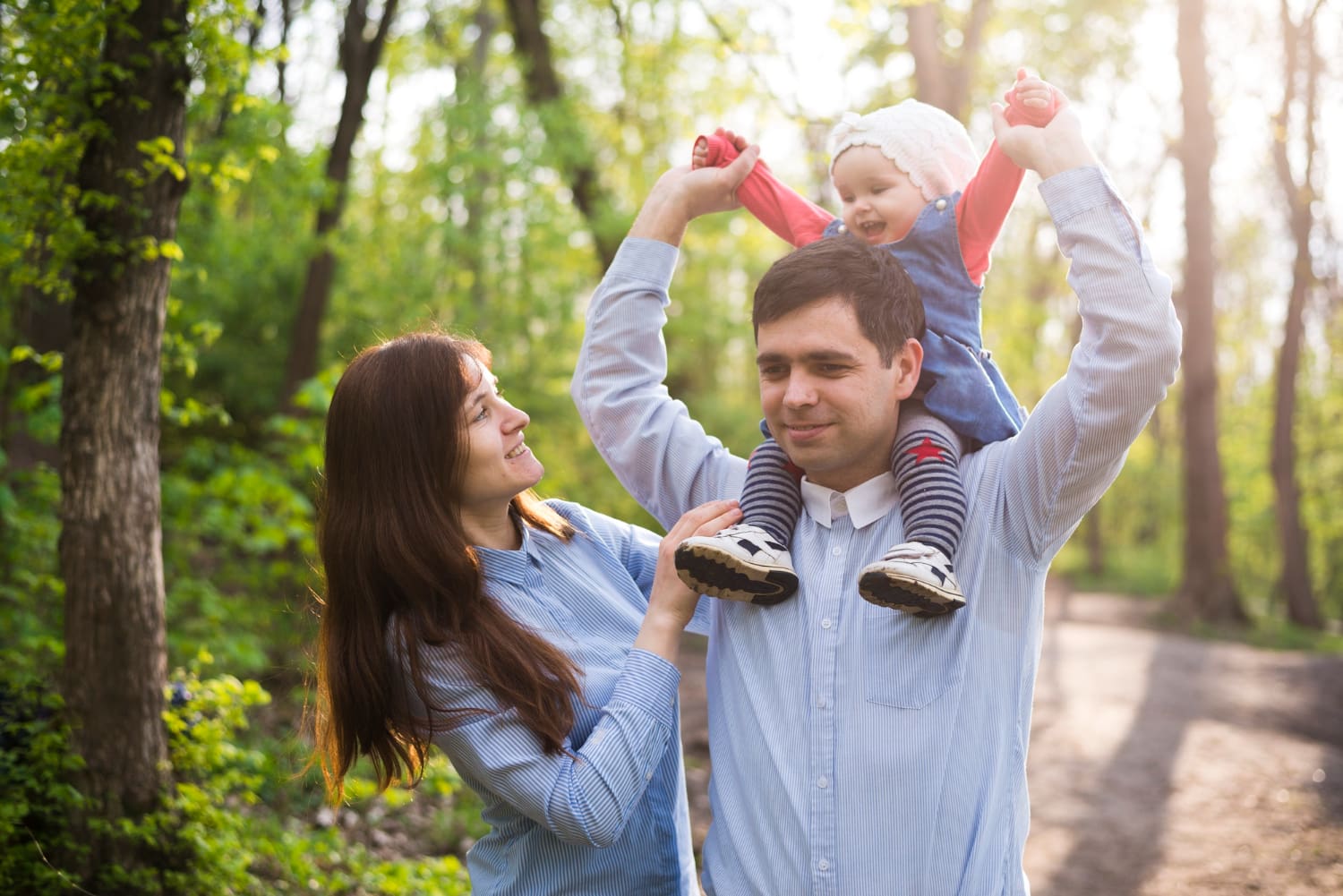 Family laughing together, dad holding toddler on his shoulders
