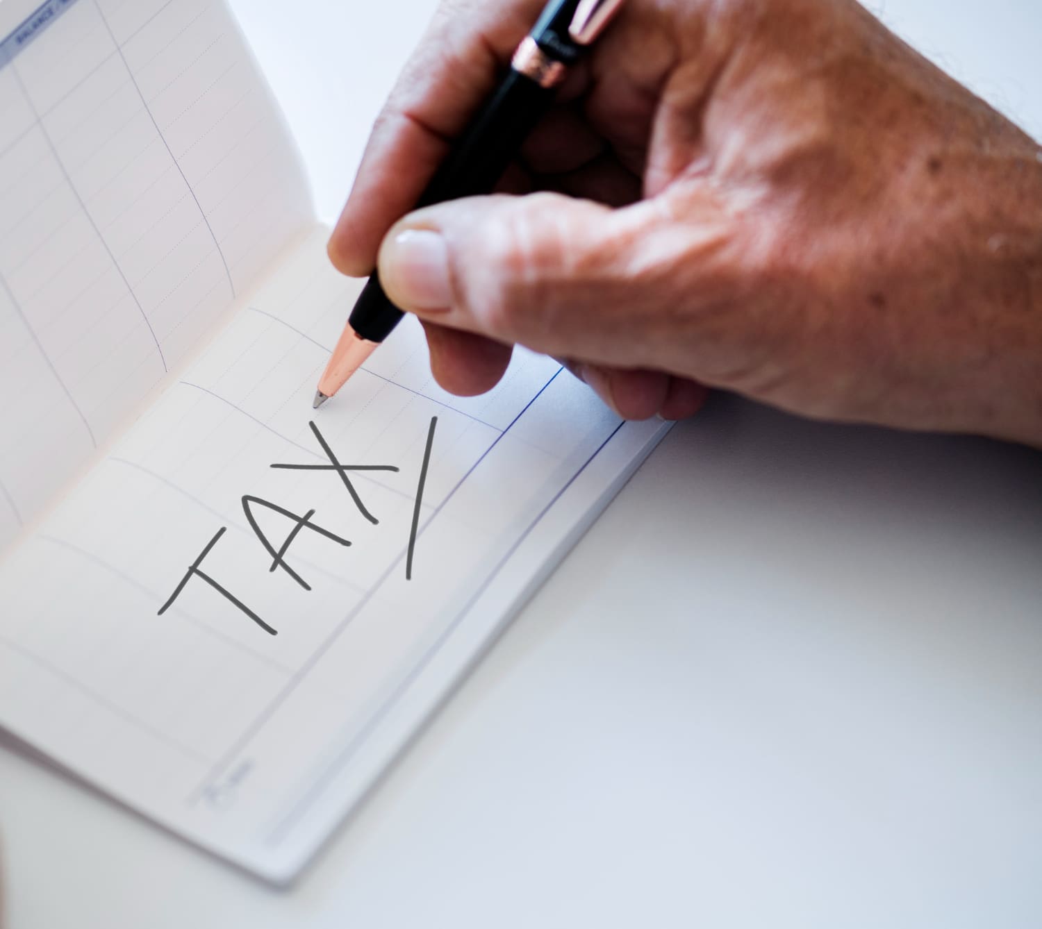 Hand signing a piece of paper that says tax on it