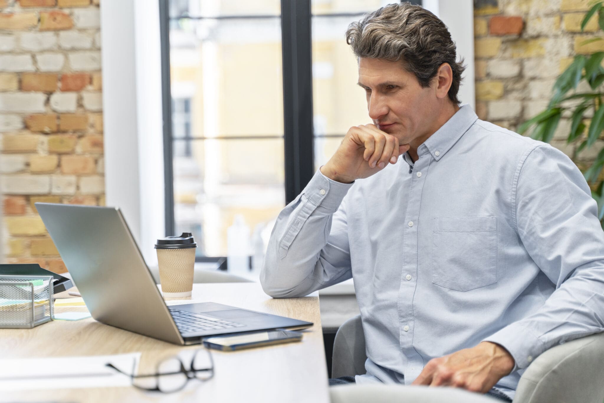 Man sitting at a desk looking at a laptop