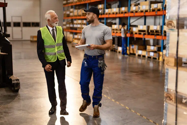 Two men discussing booking and logistics in a warehouse.