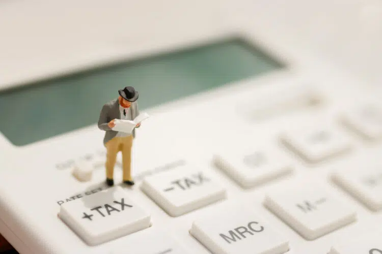 miniature accountant standing on a calculator