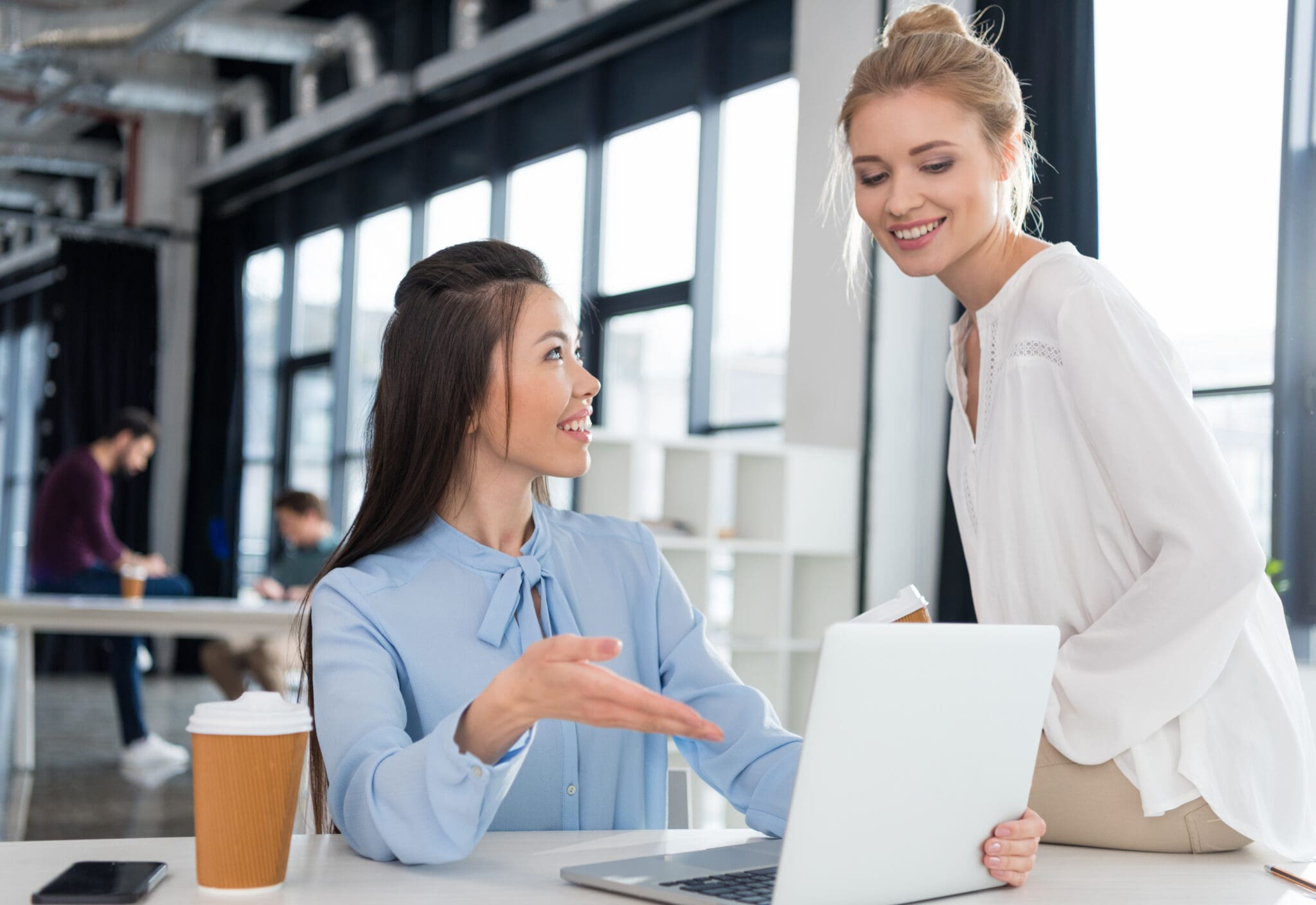 Two young accountants using a laptop amd talking
