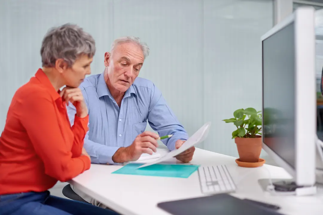 Couple checking National Insurance record with adviser to protect pension entitlement