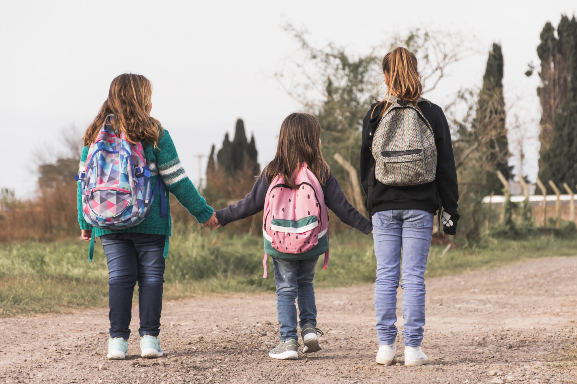Three children walking with backpacks during the school holidays